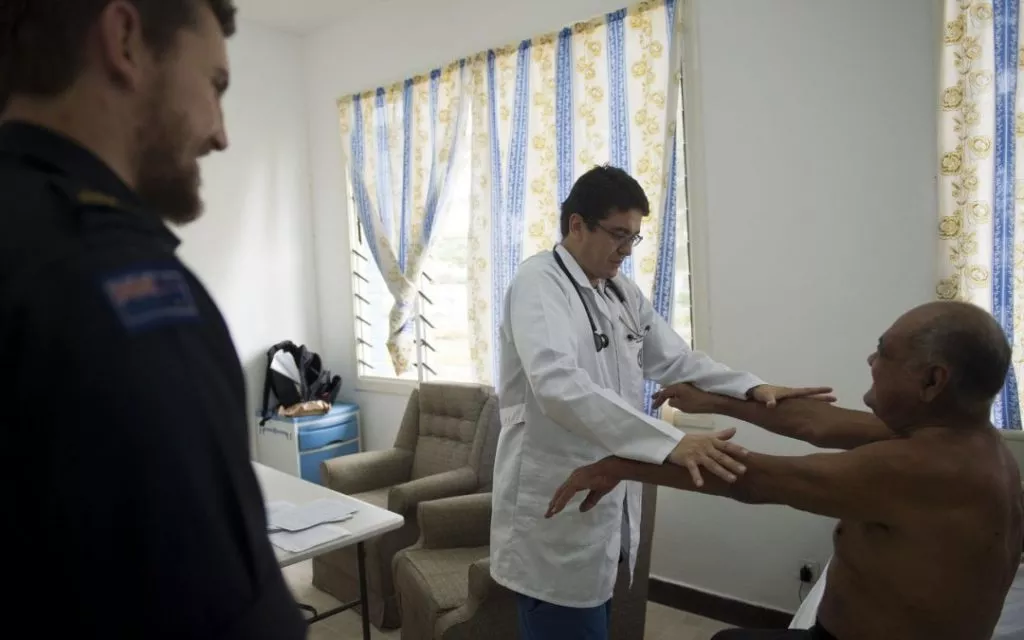 badanie następstw neurologicznych wypadku pacjent siedzi z wyciągnietymi rękami a lekarz stoi badając go